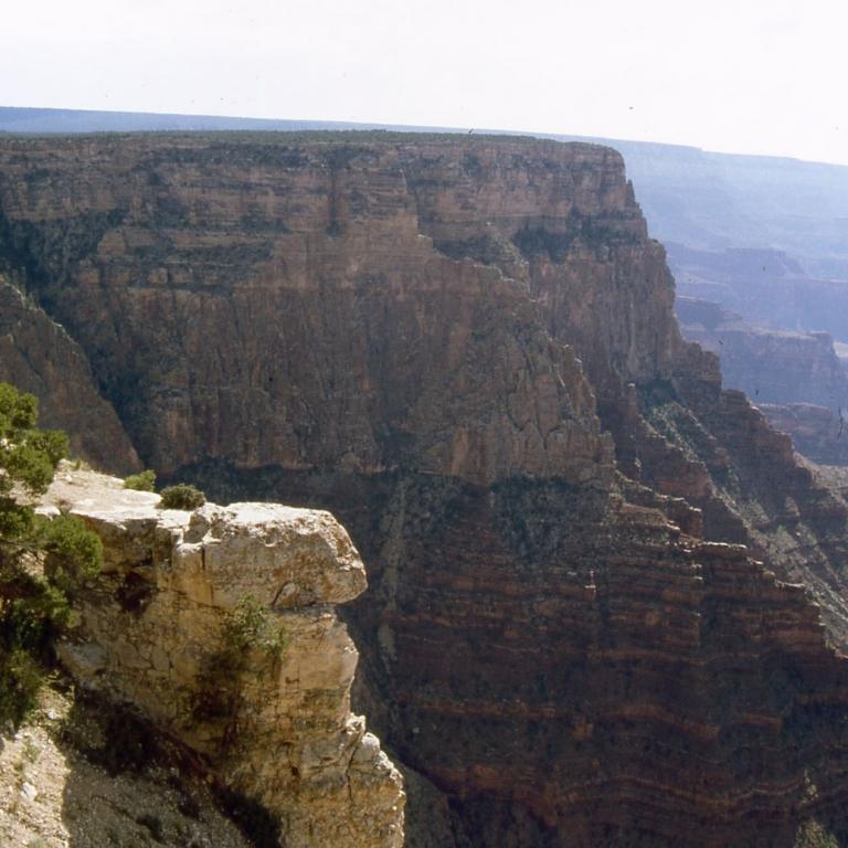 Ein weitreichender Blick von einem Felsplateau auf einen tiefen, gestaffelten Canyon.