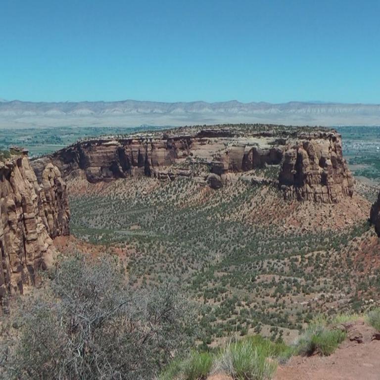 Panoramablick auf eine Canyonlandschaft mit gestuften Felsformationen und scrub-bewachsenem Gelände.