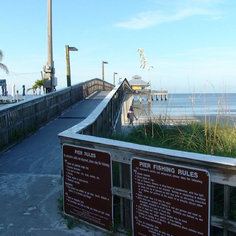 Ein langer Holzpier ragt an einem sonnigen Tag über das ruhige Meer hinaus.