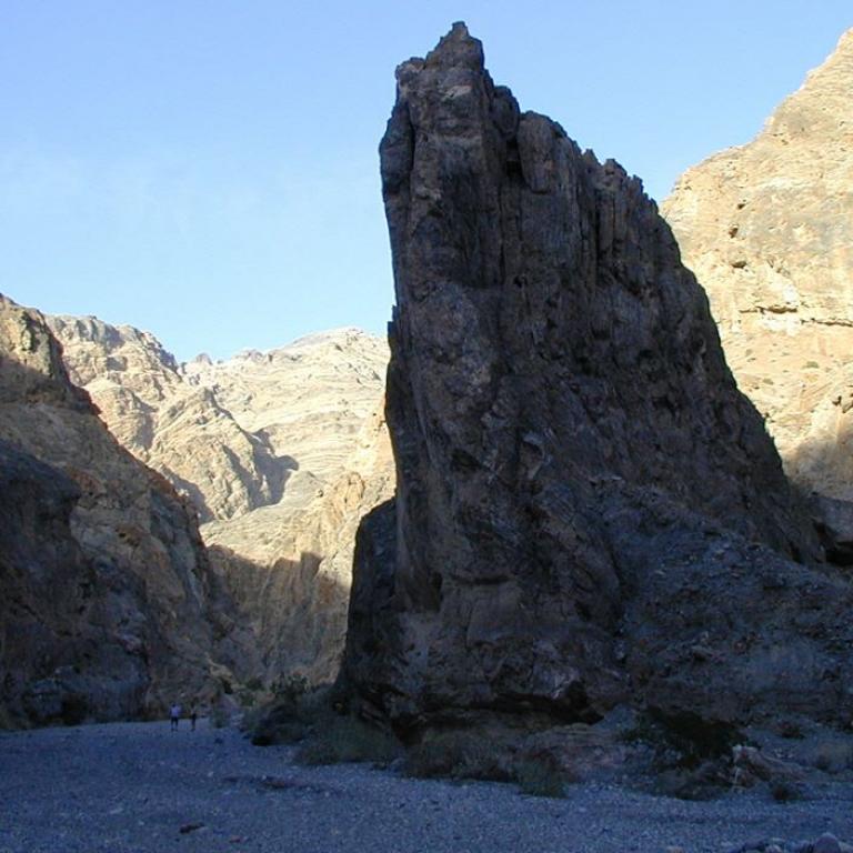 Ein steil aufragendes Felsmassiv in einem Canyon mit Blick auf weitere Gebirgsketten.