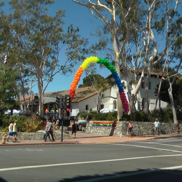 Ein bunter Regenbogen aus Luftballons spannt sich über eine Straße in einer malerischen Kleinstadt.