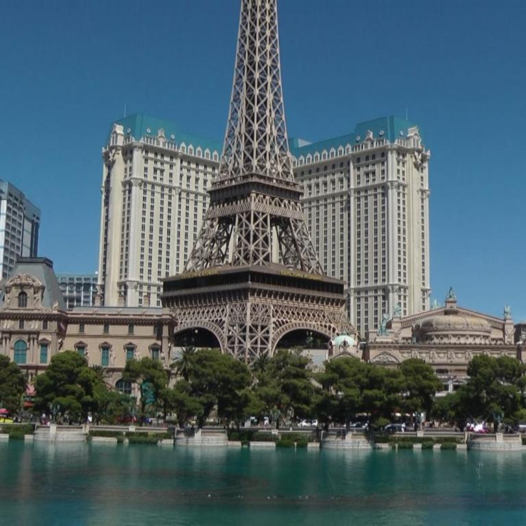 Der Eiffelturm dominiert die Skyline von Paris, sichtbar über einem Fluss, flankiert von großen historischen und modernen Gebäuden.
