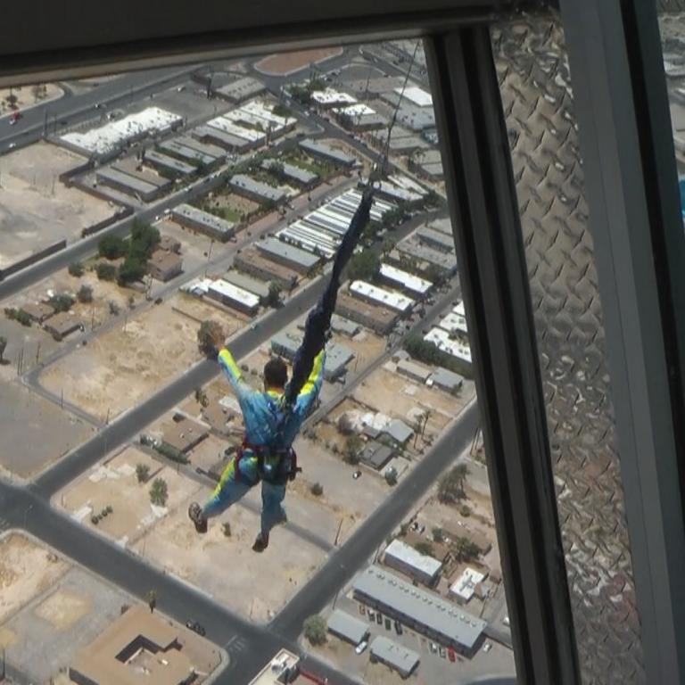 Ansicht aus einem Fenster auf eine Stadtansicht mit einer Person in der Luft.
