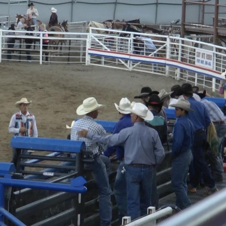 Ein Rodeo-Areal mit weißen Begrenzungsmauern und Menschen, die an einem Sportevent beteiligt sind.