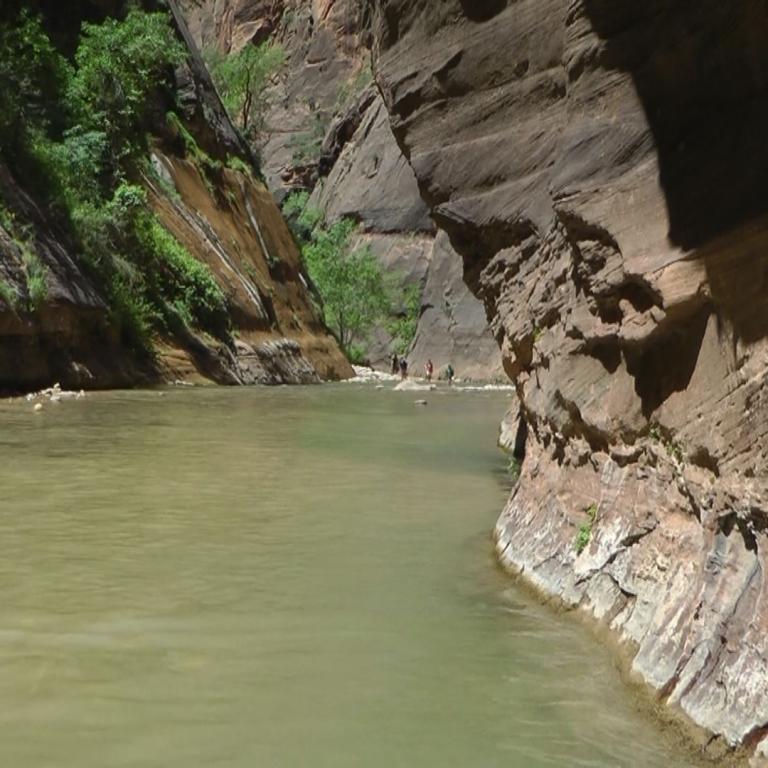 Ein breiter Fluss fließt durch eine enge Canyonlandschaft mit steilen Felswänden.