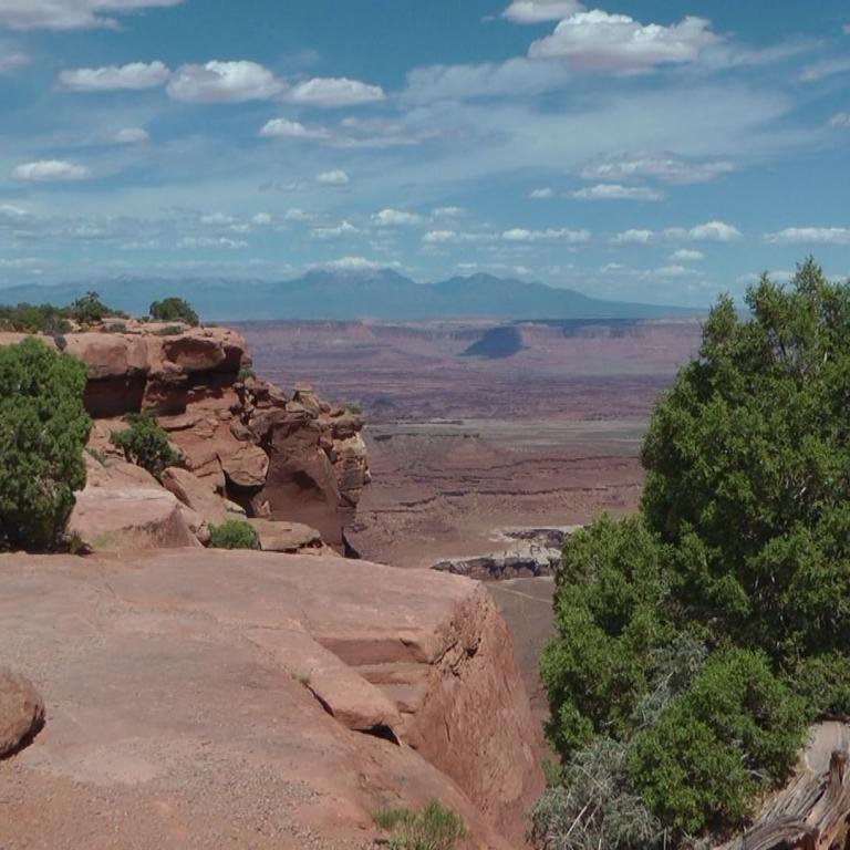 Panoramaaussicht von einem Felsvorsprung auf ein ausgedehntes Canyonplateau.
