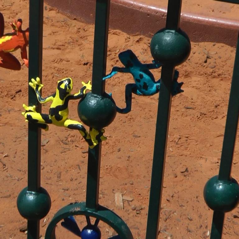 Spielgerät aus Metallgittern, verziert mit gemalten bunten Tierfiguren und einem Rad.