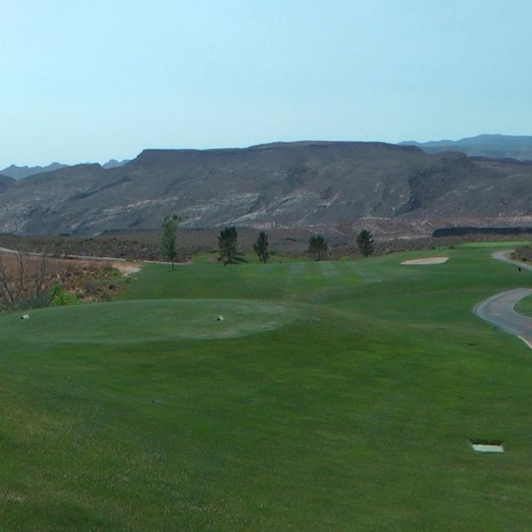 Eine weite Landschaftsaufnahme eines Golfplatzes mit einem Blick auf eine trockene Bergkette im Hintergrund.